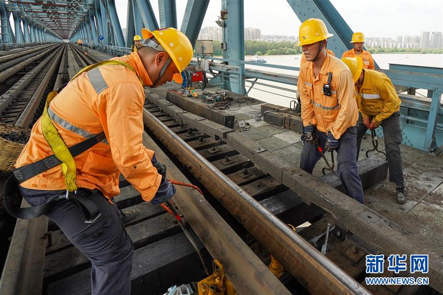 8月6日，橋隧工郭繼浩（左二）和工友在南京長江大橋作業(yè)點進行更換枕木作業(yè)。今年28歲的郭繼浩和班組其他9名工友主要負(fù)責(zé)南京長江大橋鐵路橋梁設(shè)備的日常巡查、養(yǎng)修和臨時性搶修等工作。　　連日來，江蘇省南京市持續(xù)高溫天氣，在中國鐵路上海局集團有限公司南京橋工段南京大橋車間，近80名橋隧工不畏高溫酷暑，堅守崗位，確保暑運列車的安全運行。戴著安全帽，穿著防護服，橋隧工們趁著沒有列車運行的“天窗時間”，每天用腳步“丈量”大橋，保障長江大橋鐵路橋運輸暢通、安全。新華社記者 李博 攝