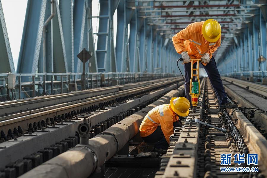 8月6日，兩名橋隧工在南京長江大橋作業(yè)點擰緊螺帽，固定護木。新華社記者 李博 攝