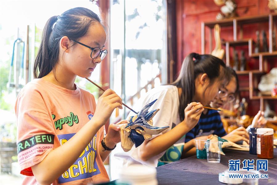 8月9日，貴州省安順市第一高級中學的學生在安順市儺雕文化博物館為儺戲面具上色。新華社發(fā)（陳熙 攝）
