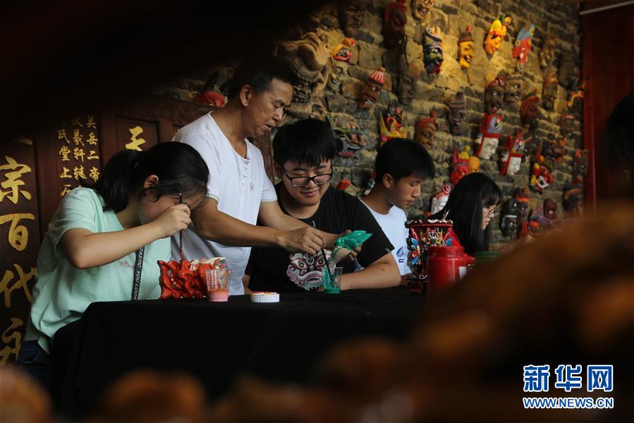 8月9日，在貴州省安順市儺雕文化博物館，非遺傳承人秦發(fā)忠（左二）指導安順市第一高級中學的學生給儺戲面具上色。新華社發(fā)（程洪凱 攝）