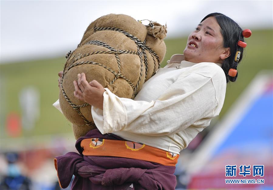8月10日，一名婦女在參加抱石頭比賽。當(dāng)日，2020年那曲羌塘恰青格薩爾賽馬藝術(shù)節(jié)在西藏那曲市格薩爾賽馬場(chǎng)開幕，來自那曲各縣區(qū)的農(nóng)牧民在賽馬場(chǎng)參加了抱石頭比賽和押加賽。新華社記者 張汝鋒 攝