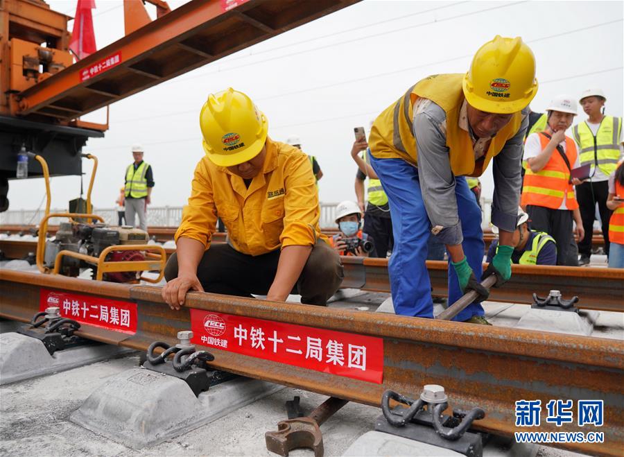 8月17日，中鐵十二局工人在進行鋪軌作業(yè)。 當日，京雄城際鐵路最后一組500米長鋼軌在河北雄安新區(qū)鋪設完成，標志著京雄城際鐵路全線軌道貫通。 新華社記者 牟宇 攝