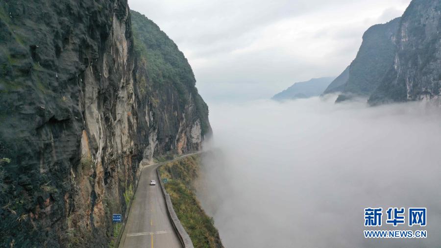 11月18日，車輛行駛在湖北省鶴峰縣的雕崖公路上。雕崖公路位于湖北省恩施土家族苗族自治州鶴峰縣境內(nèi)，全長(zhǎng)約3公里，是巴鶴（巴東縣至鶴峰縣）公路中的一段。這里峽谷深臥、絕壁聳峙、云霧繚繞。雨后初晴，車行雕崖公路上宛如穿行在云霧中，成為一道美麗的風(fēng)景線。新華社發(fā)（楊順丕 攝）