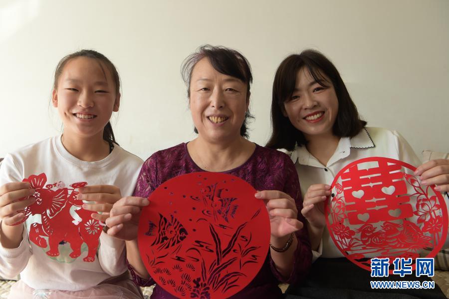 　　2月21日，在烏海市海南區(qū)新橋花園，李華（中）與外孫女高宇晨（左）、大女兒譚紅葉一起展示剪紙作品。新華社記者 李志鵬 攝