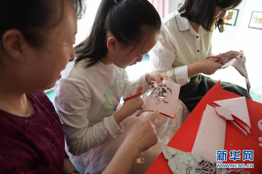 　　2月21日，在烏海市海南區(qū)新橋花園，李華（左）在家中指導(dǎo)外孫女高宇晨（中）剪紙。新華社記者 李志鵬 攝
